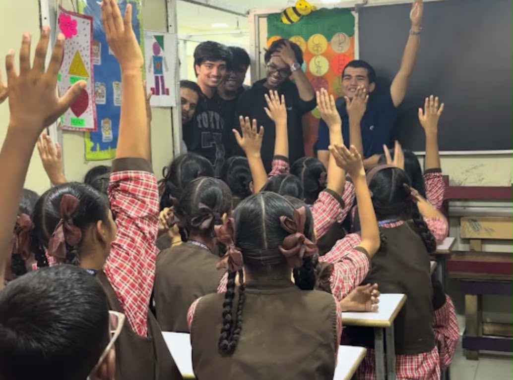 Students raise their hands during a Nacht session while the mentors smile at the back of the classroom